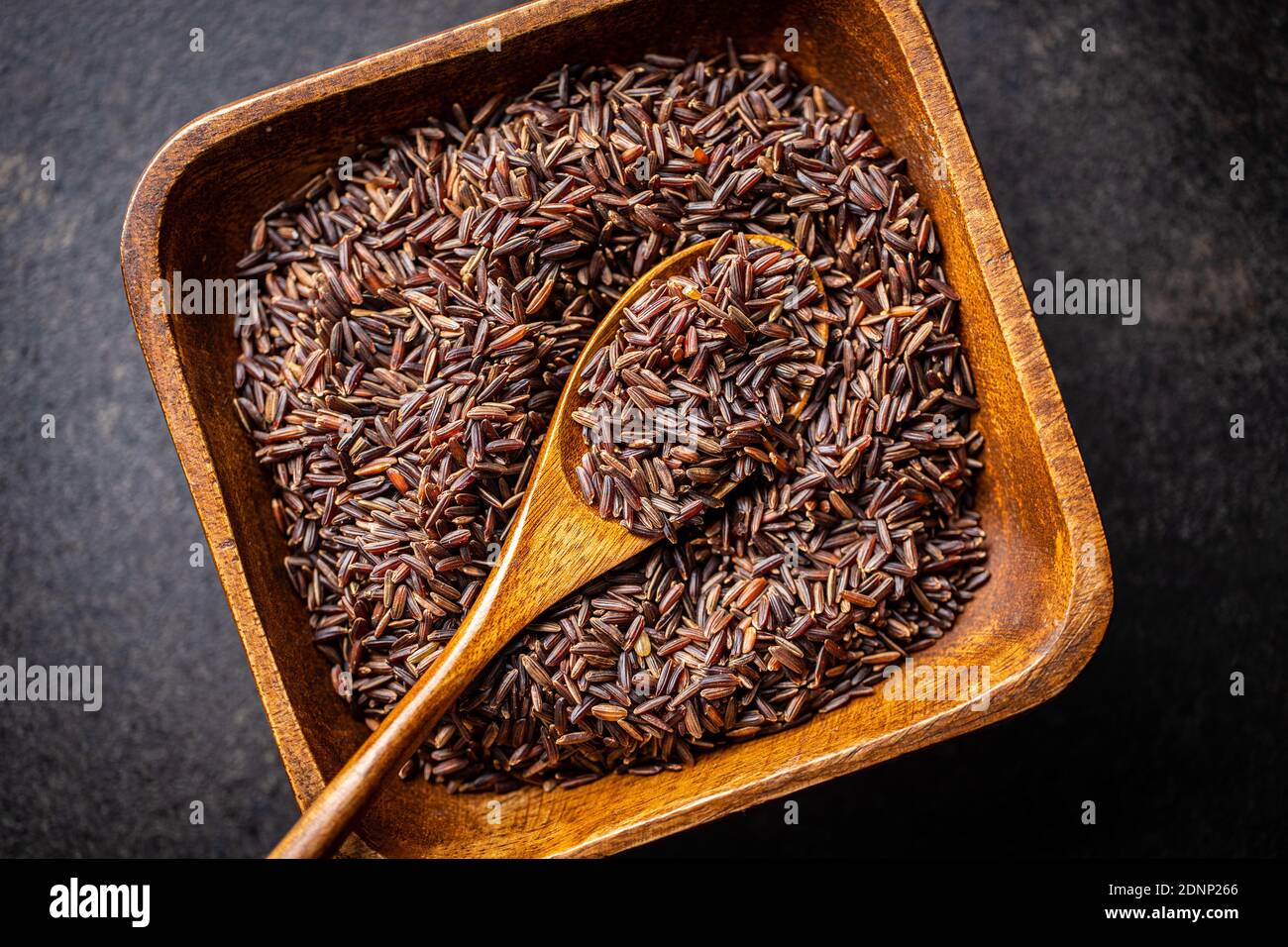 Uncooked red rice. Raw wild rice in bowl. Top view. Stock Photo