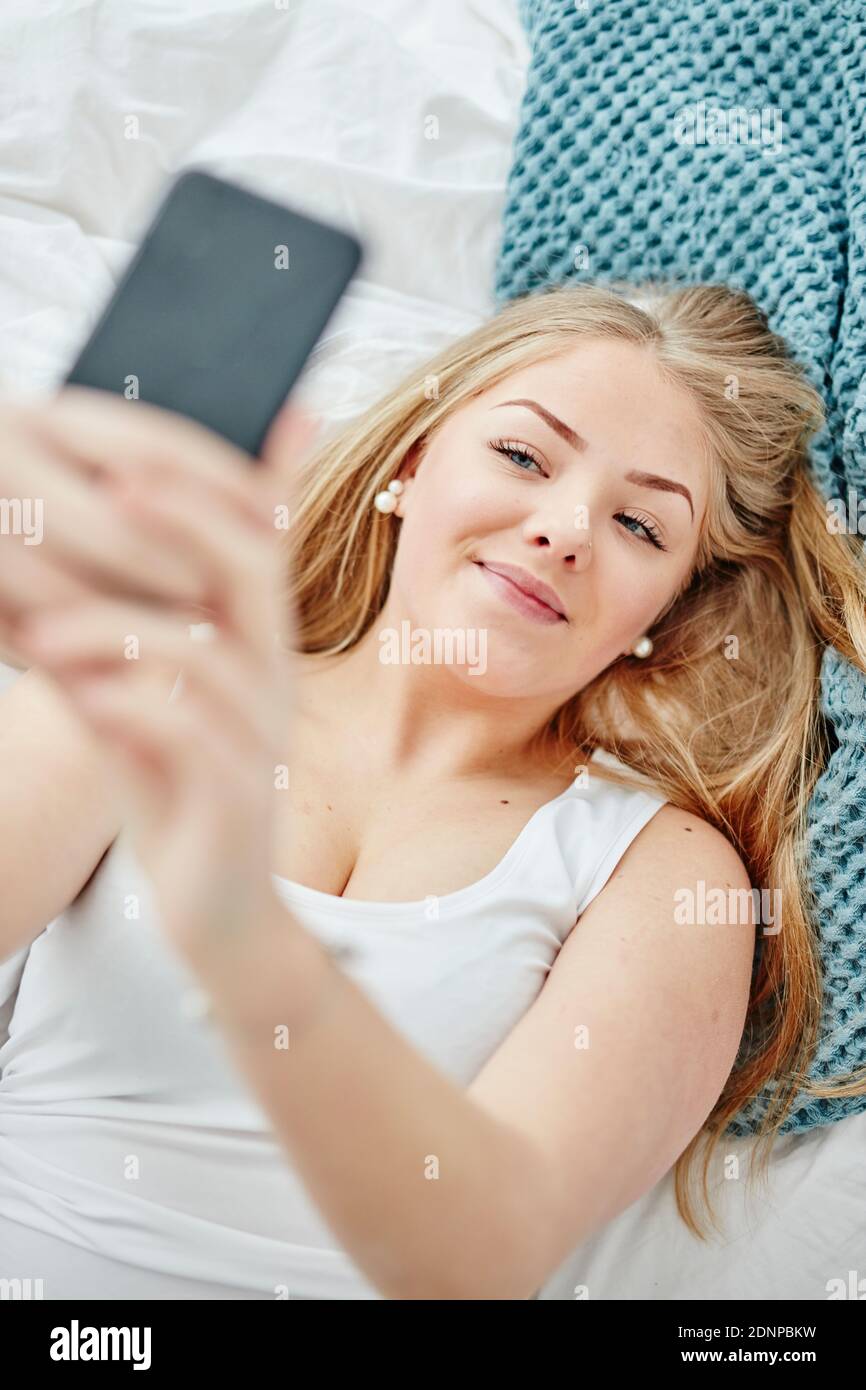 Woman in bed taking selfie Stock Photo