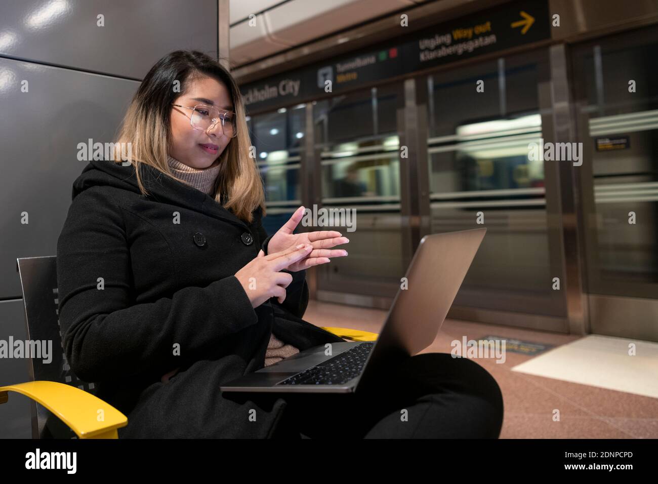 Woman at train station using laptop Stock Photo