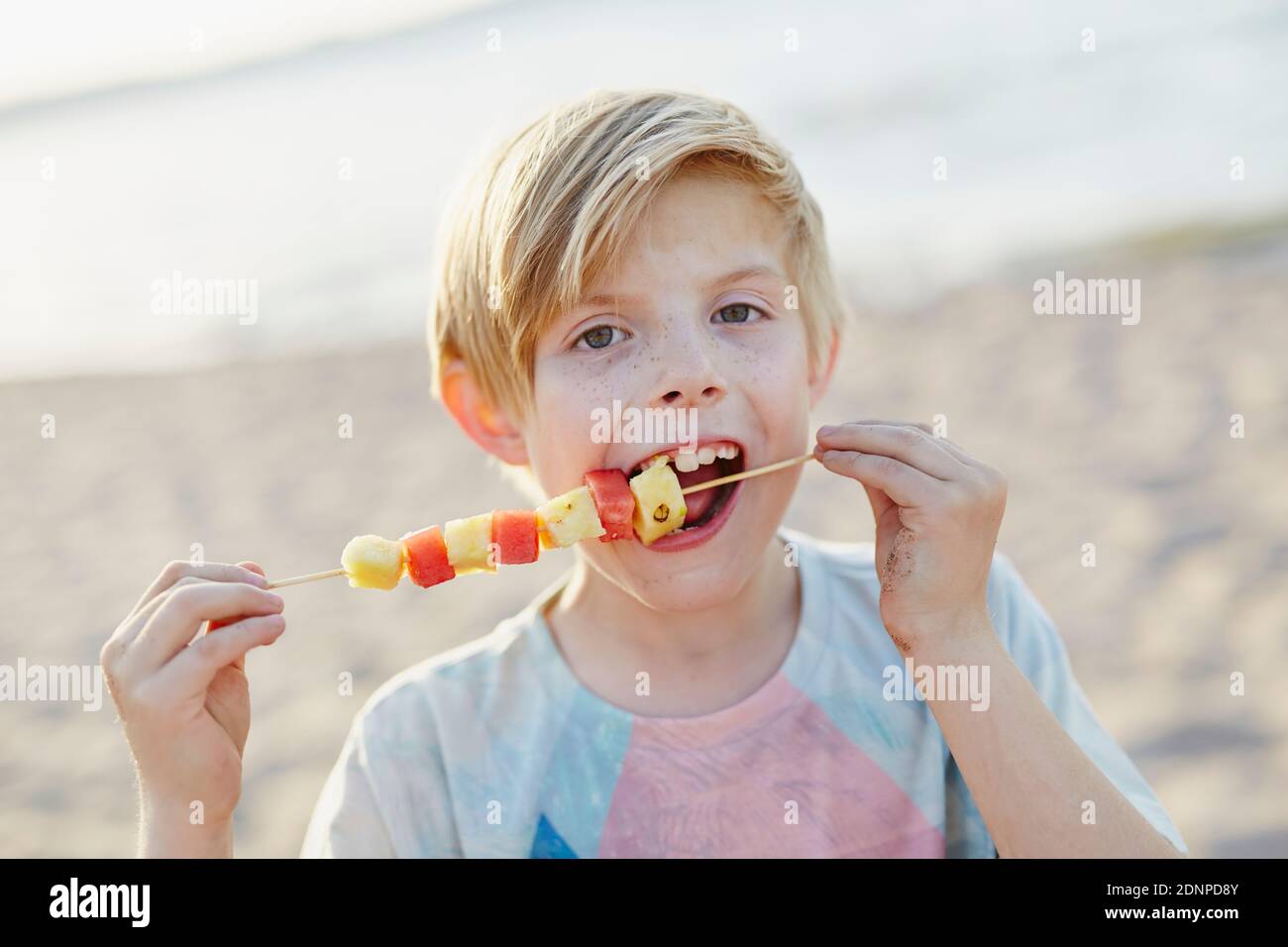 Boy eating fruit kebab Stock Photo