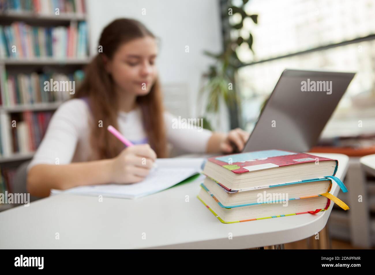 Selective focus on books, teen girl using laptop while studying at the  library on background. Intelligence, knowledge concept Stock Photo - Alamy