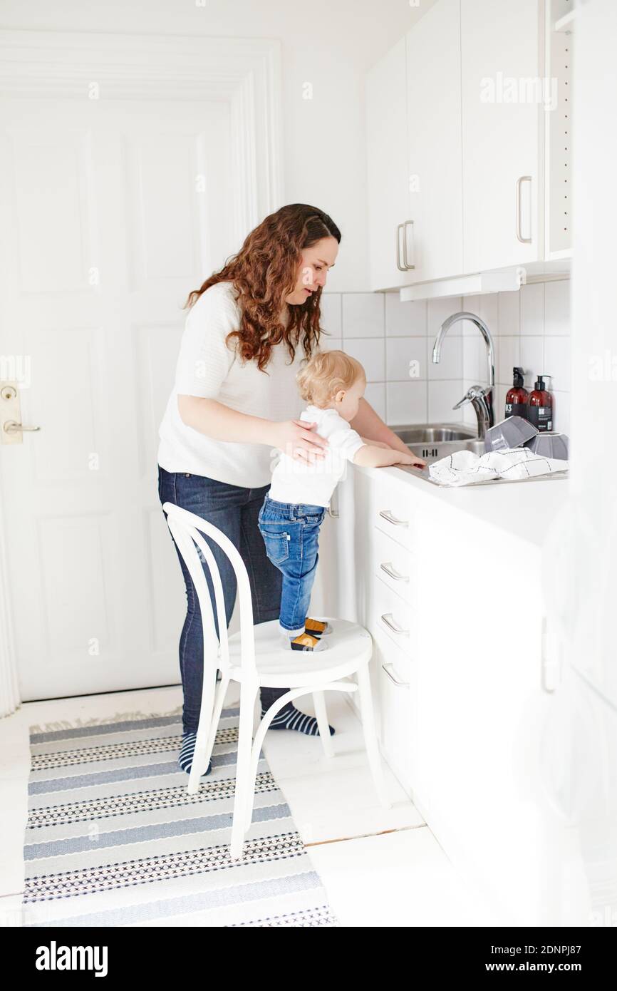 Mother and toddler son washing dishes Stock Photo