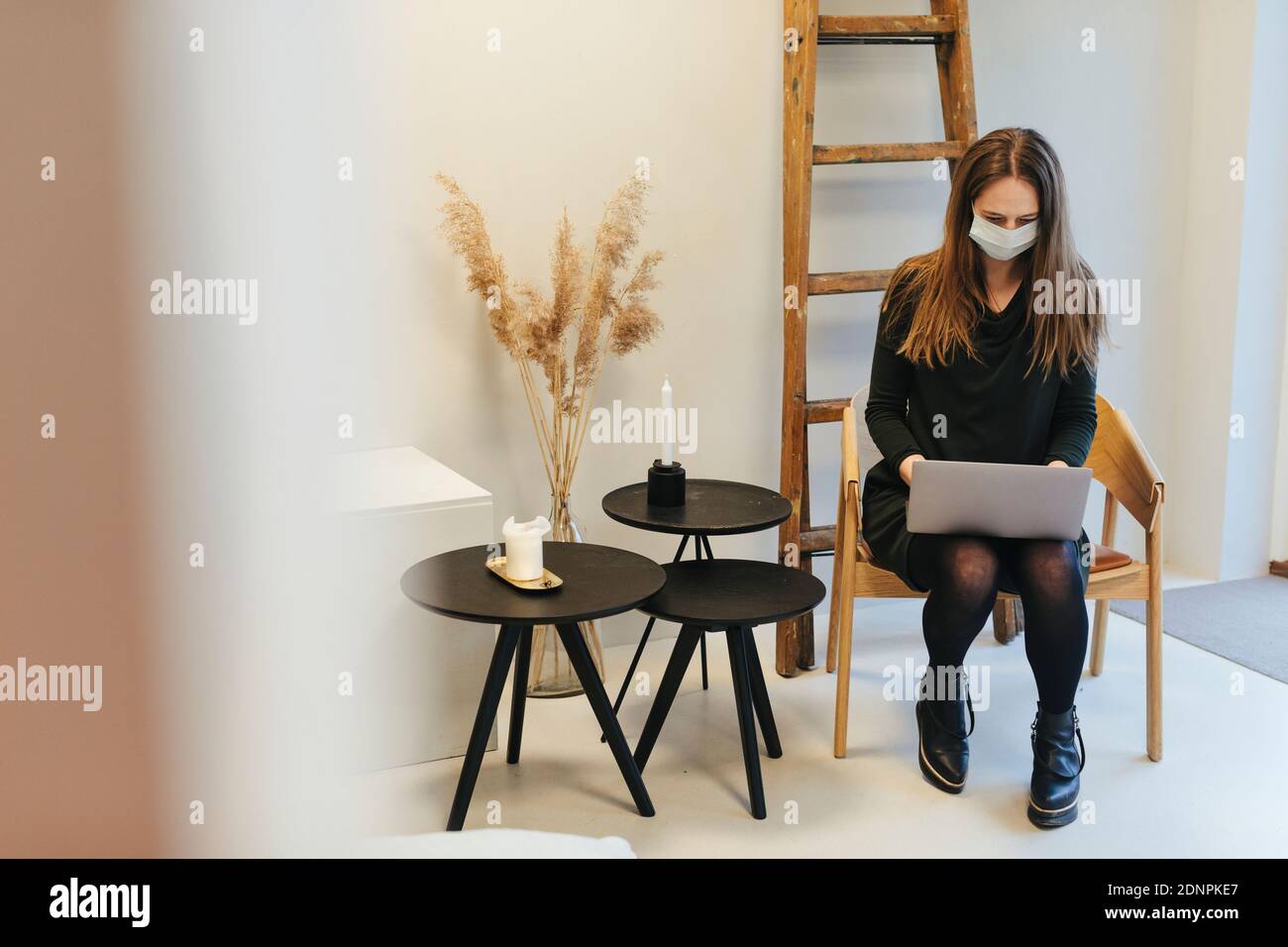 Woman wearing protective mask using laptop Stock Photo