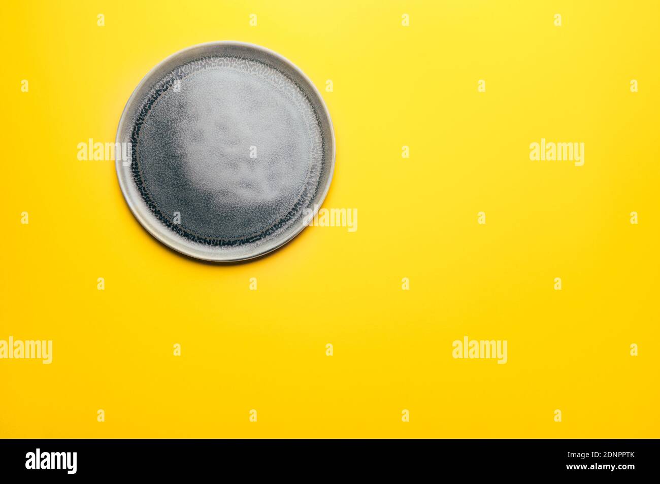 Gray empty ceramic plate on yellow Stock Photo