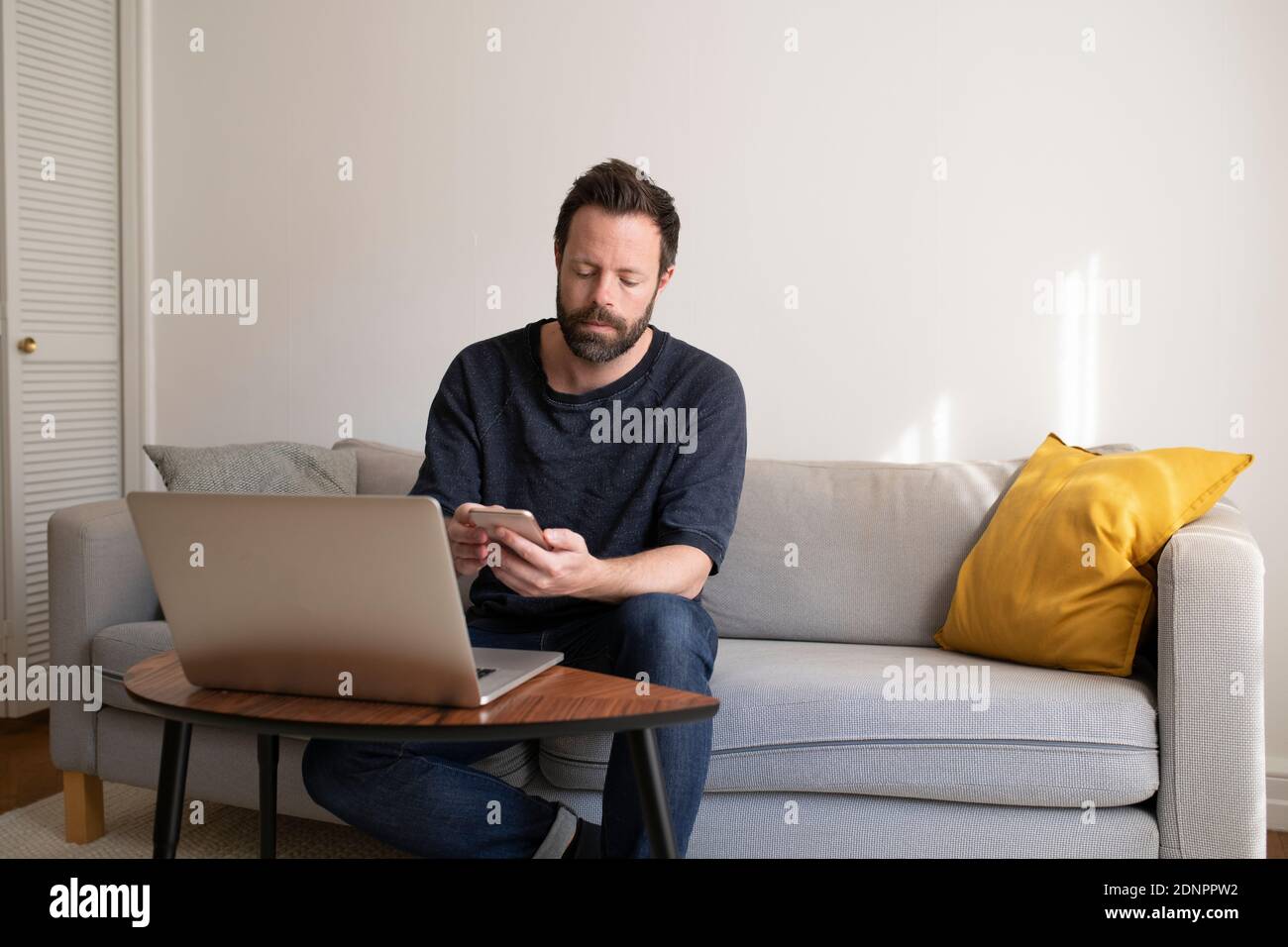 Man on sofa using cell phone Stock Photo