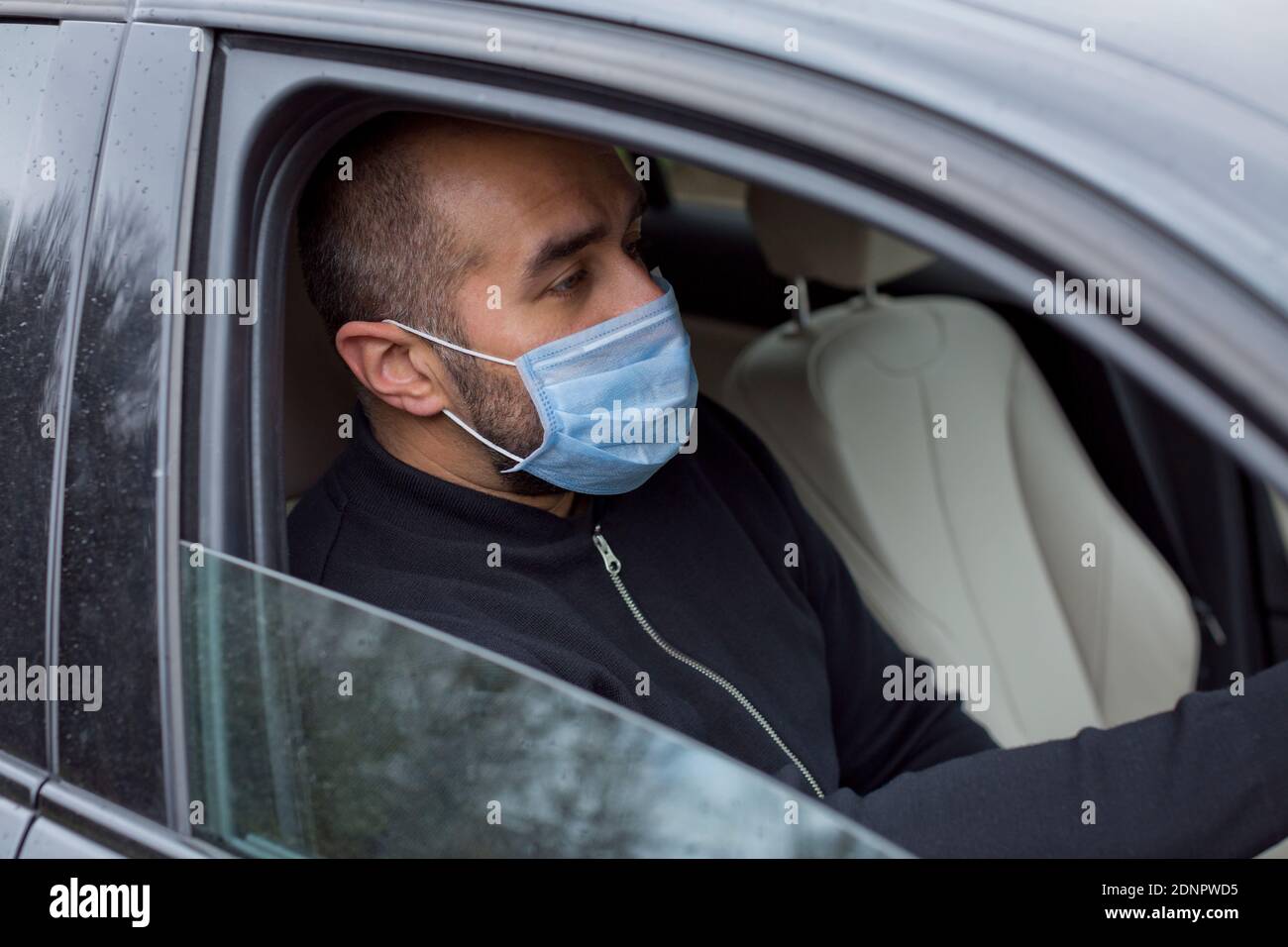 Man wearing protective mask in car Stock Photo