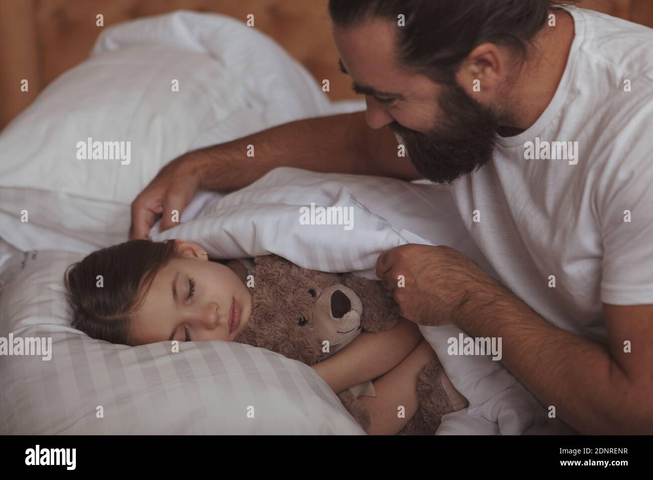 Loving father tucking blanket for his lovely little daughter. Adorable