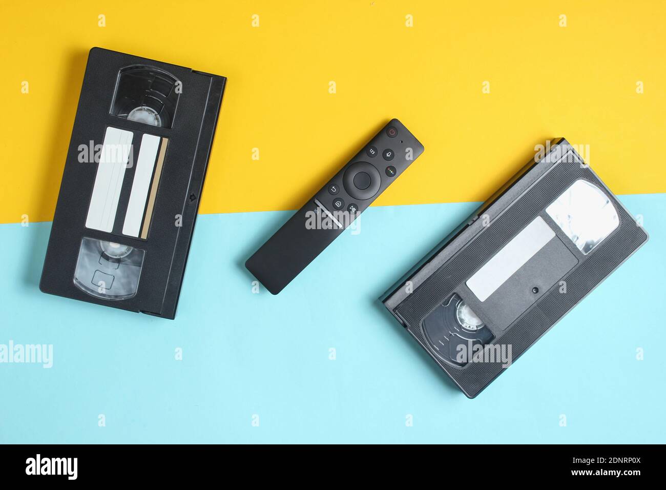 Tv remote and video cassettes on a colored pastel background Top view, minimalism Stock Photo