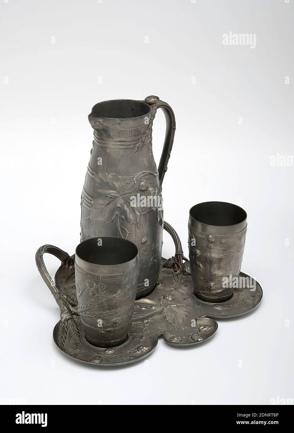 Jules Brateau, beer service with hops and barley decoration, Acquired by the artist at the world exhibition in Paris in 1900, pewter, poured, polished, Object (jug): Height: 24.4 cm; Diameter: 10.4 cm, Stamp: on the tray in the base for the jug and on the underside of the jug and mugs JULES BRATEAU, Stamp: on the bottom of the tray and the jug as well as on the inside bottoms of the cups: gallows and hanged persons, drinking and barware, plants, vegetation, cereal, grain, art nouveau Stock Photo