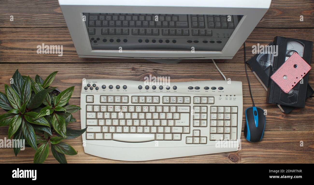 Retro computer on wooden table. Monitor, keyboard, pc mouse, pot with ...
