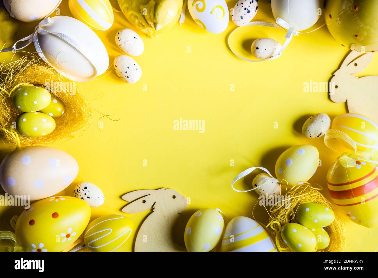 Easter egg and Easter bunny decorations arranged on a yellow background Stock Photo