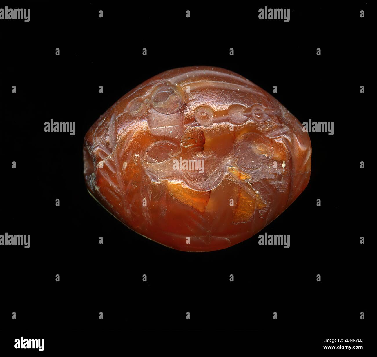 Stamp seal (Bezoar goat hit by a throwing spear), Kunststitfung, Carnelian, cut, drilled, Total: Height: 1,64 cm; Width: 2,02 cm; Depth: 0,88 cm, Body ornamentation, glyptic, goat, Capricorn, The intaglio shows a standing Bezoar goat or Capricorn on the front side. The animal is surrounded by branches, undergrowth or plants. In its neck is a throwing spear. The small rings indicate a knot shaft. A whole group of gems shows only the hit animal; mostly it is wild goats, ibexes or antelopes, rarely cattle. Stock Photo