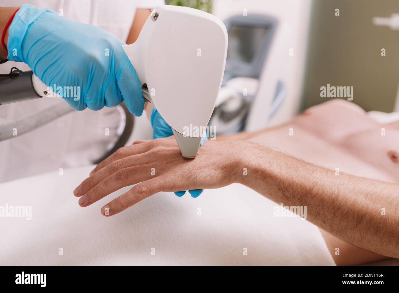 Cropped shot of a cosmetologist removing hair on the hand of a male client, using laser hair removal device Stock Photo