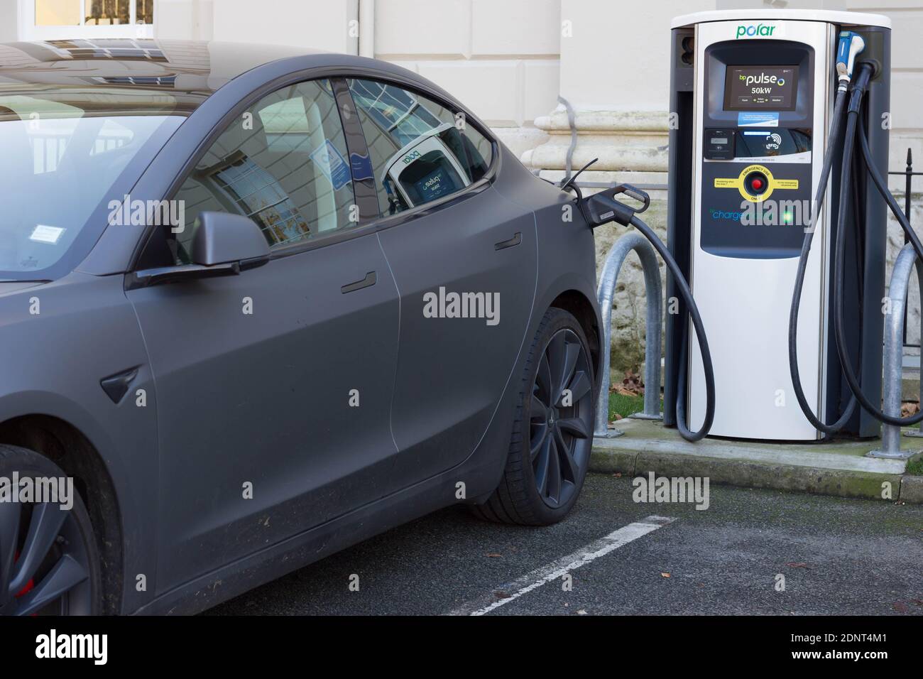 grey Tesla electric car plugged into charging station at Queen's house
