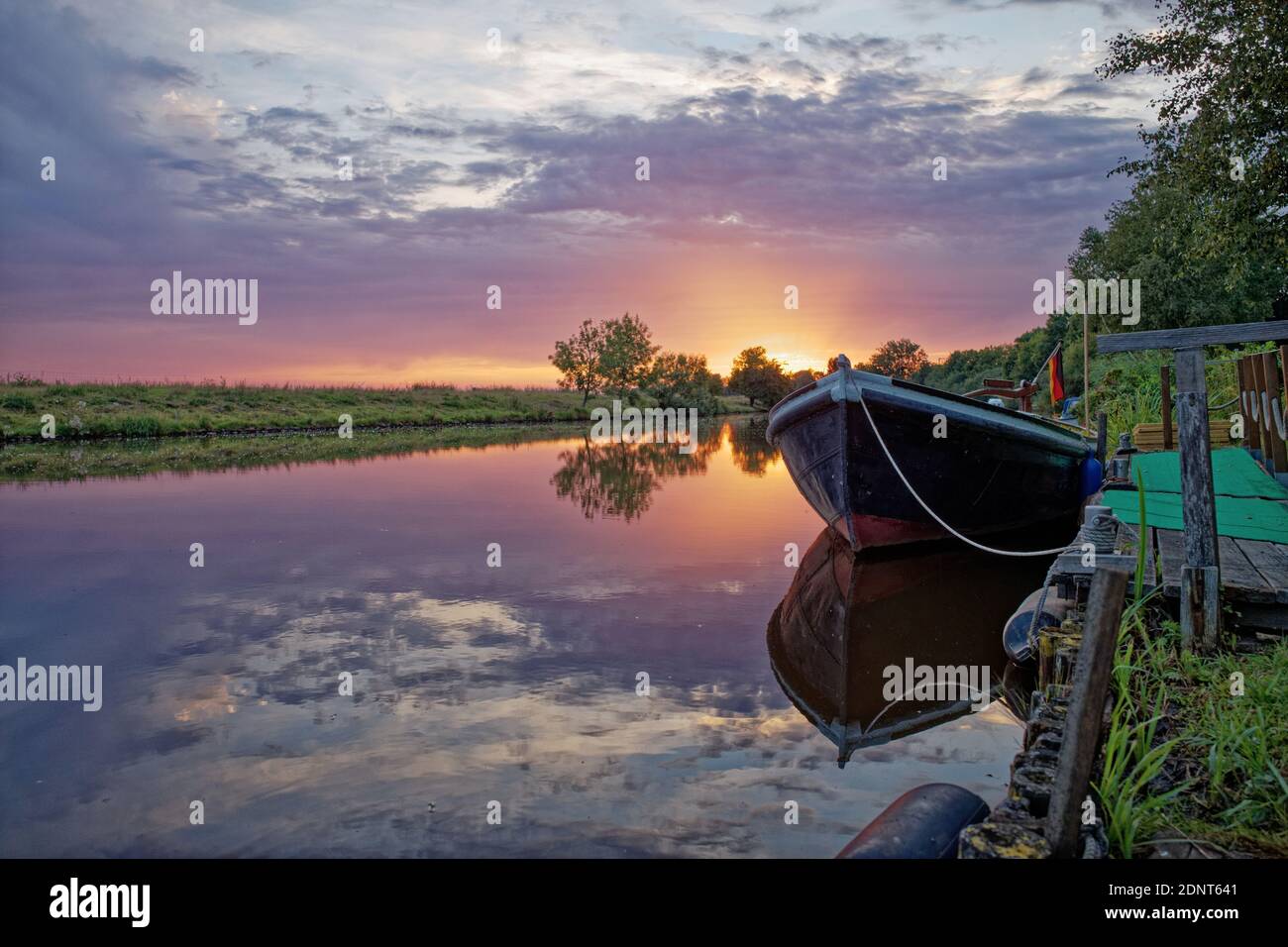 Boat moored along riverbank at sunset, East Frisia, Lower Saxony, Germany Stock Photo