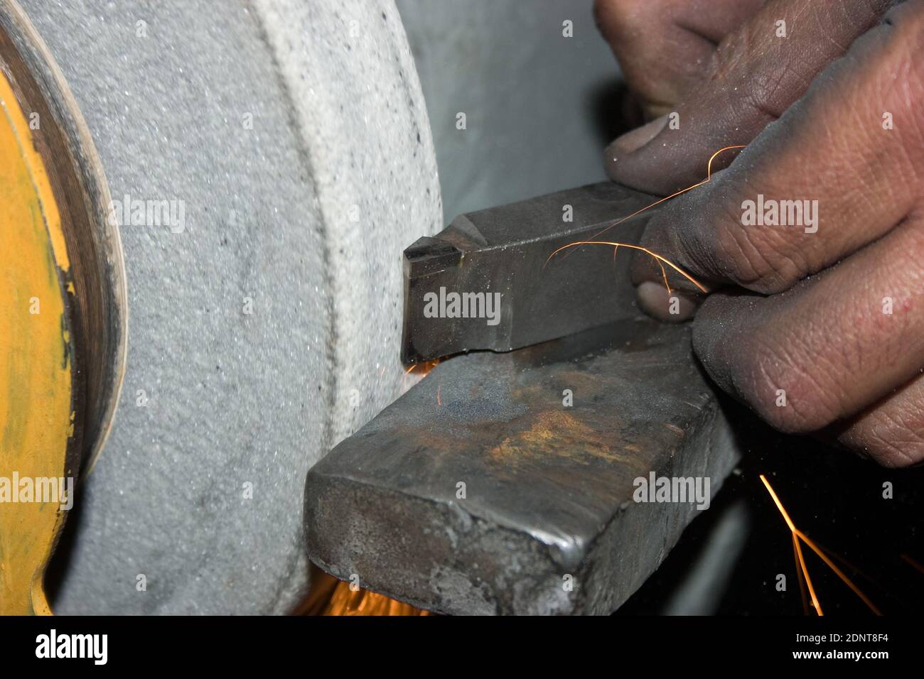 Sharpening a turning tool. Worker's hands are grinding a turning tool