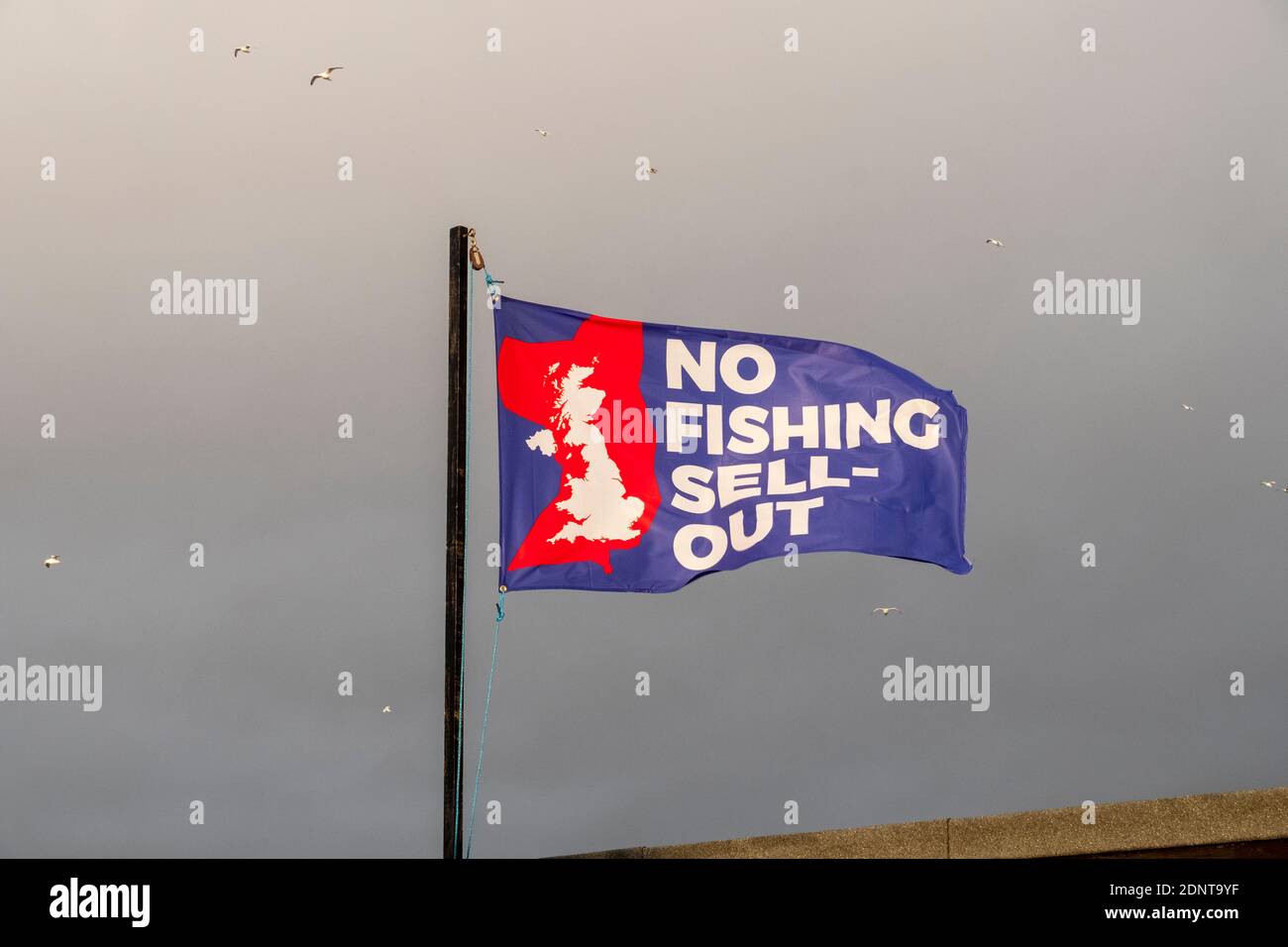 Hastings; East Sussex UK. 18th December 2020. Dark clouds gather on a mild windy morning, over the fishermen's beach. Fishing rights are still a sticking point in the EU Brexit negotiations. Carolyn Clarke/Alamy Live News. Brexit flag Stock Photo