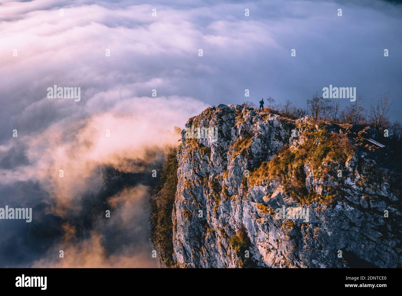 Man standing on mountain ridge rising above the cloud carpet, Hallein, Salzburg, Austria Stock Photo