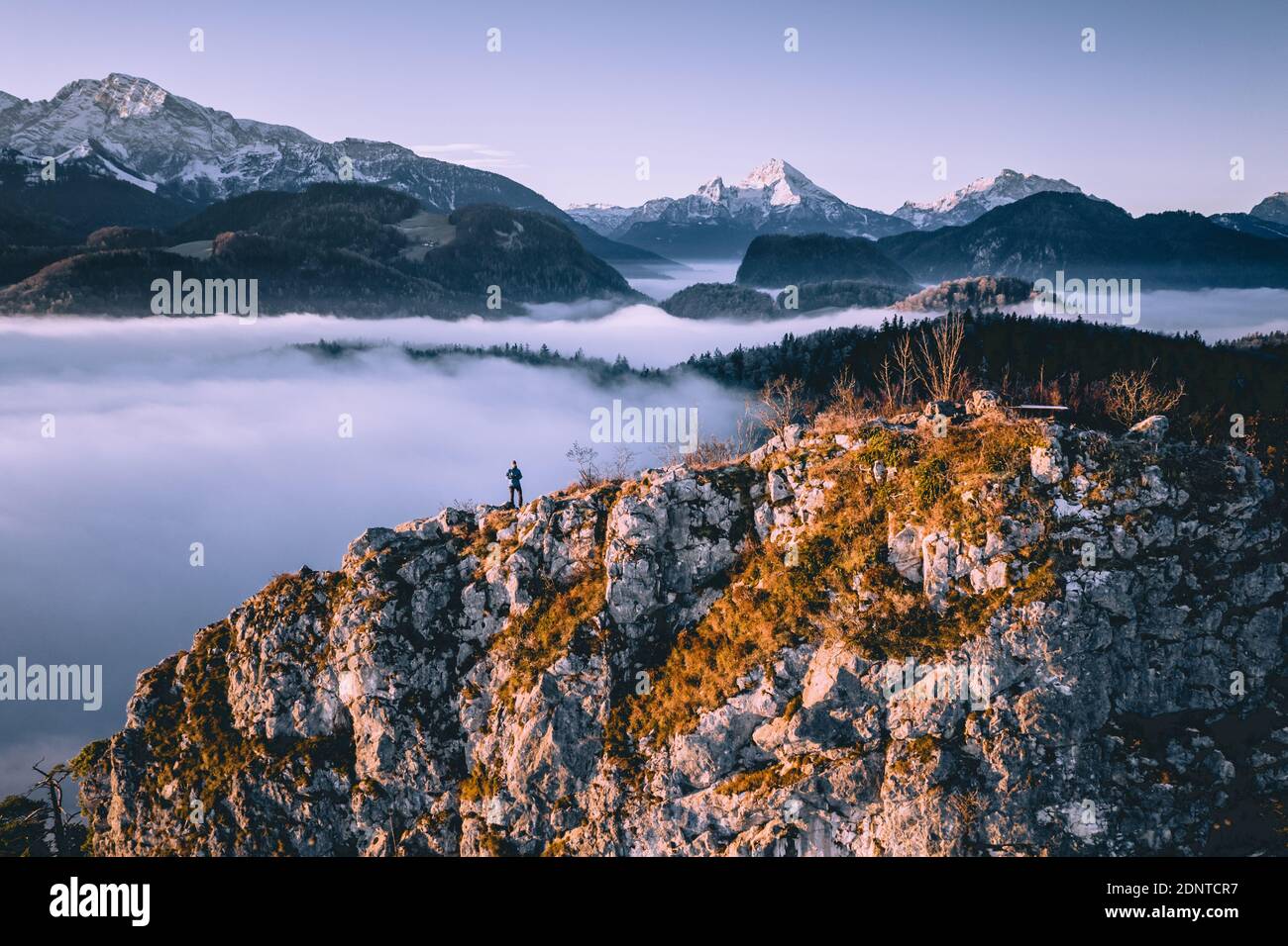 Man standing on mountain ridge rising above the cloud carpet, Hallein, Salzburg, Austria Stock Photo