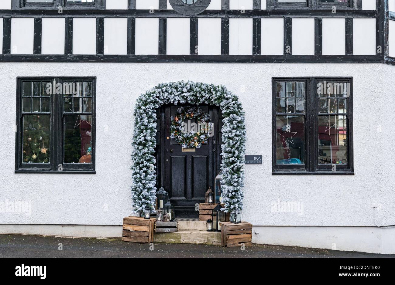 Aberlady, East Lothian, Scotland, United Kingdom, 18th December 2020. Christmas decorations: an unusual timber framed house in the village is richly decorated for the festive season with a garland around the door and a Christmas wreath Stock Photo