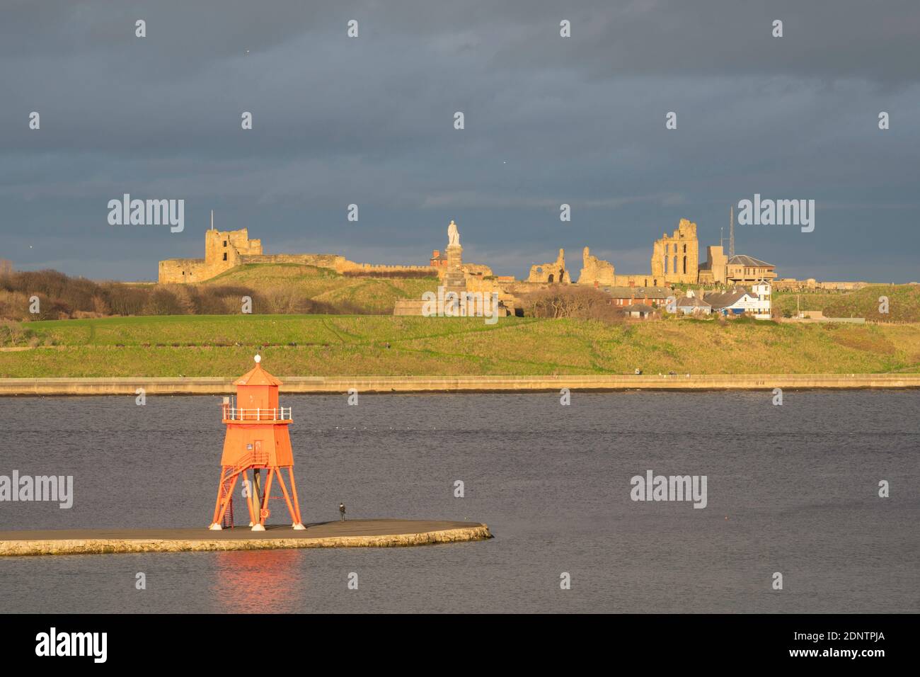 The Herd Groyne lighthouse and Tynemouth castle and priory buildings seen from South Shields, north east England, UK Stock Photo