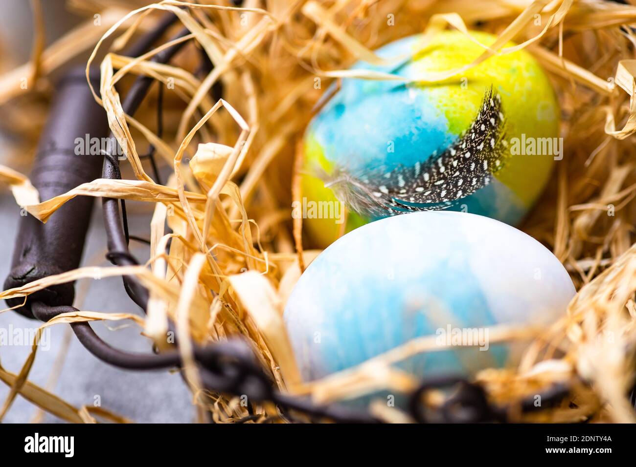 Multi coloured Easter eggs in a basket surrounded with straw Stock Photo