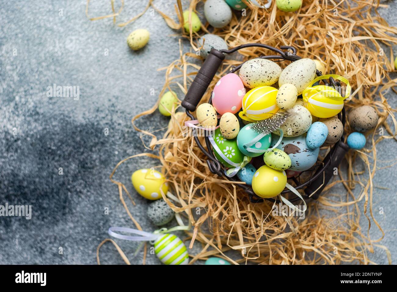 Multi coloured Easter eggs in a basket surrounded with straw Stock Photo