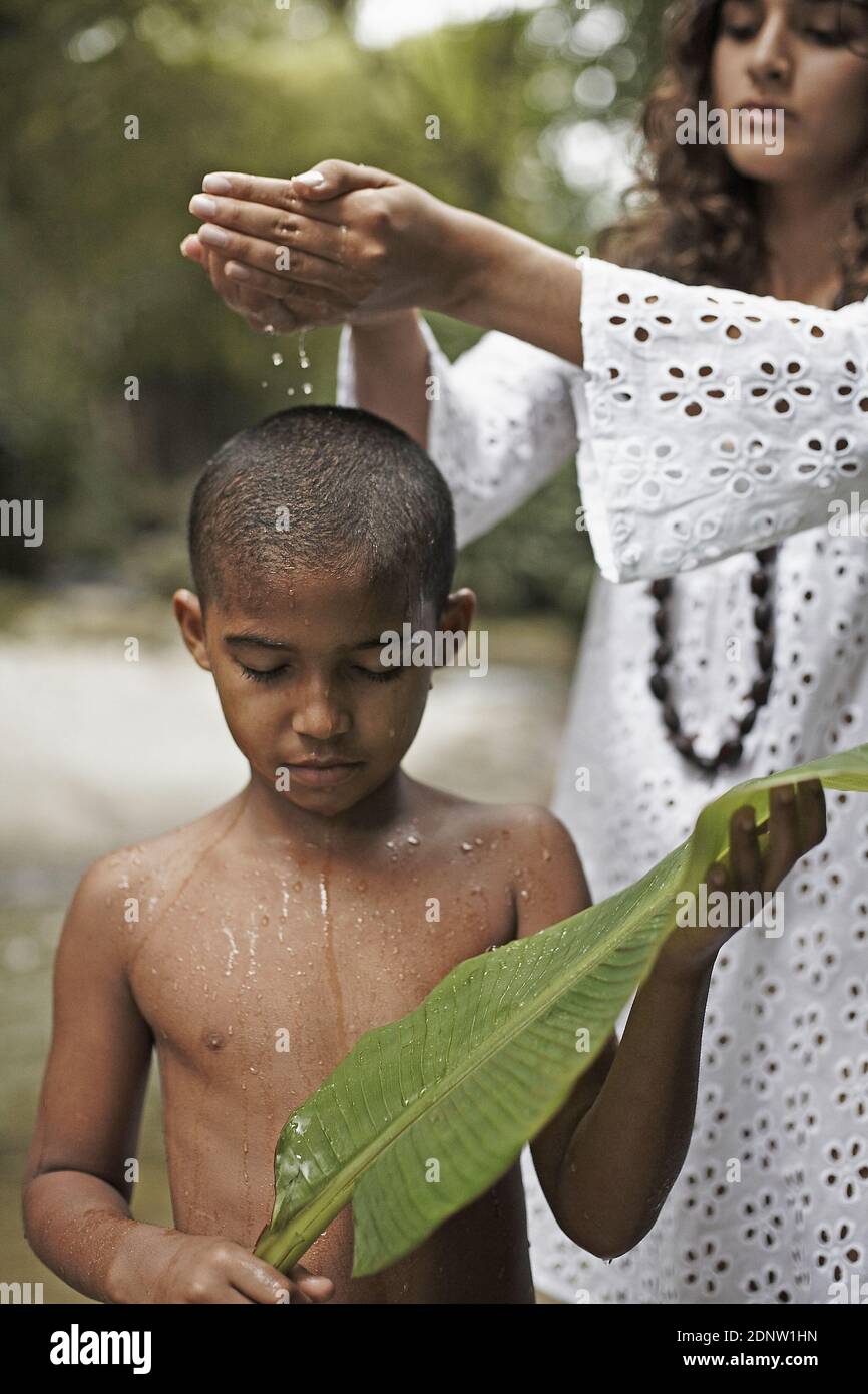 young beautiful mother pouring water over the head of her son Stock Photo