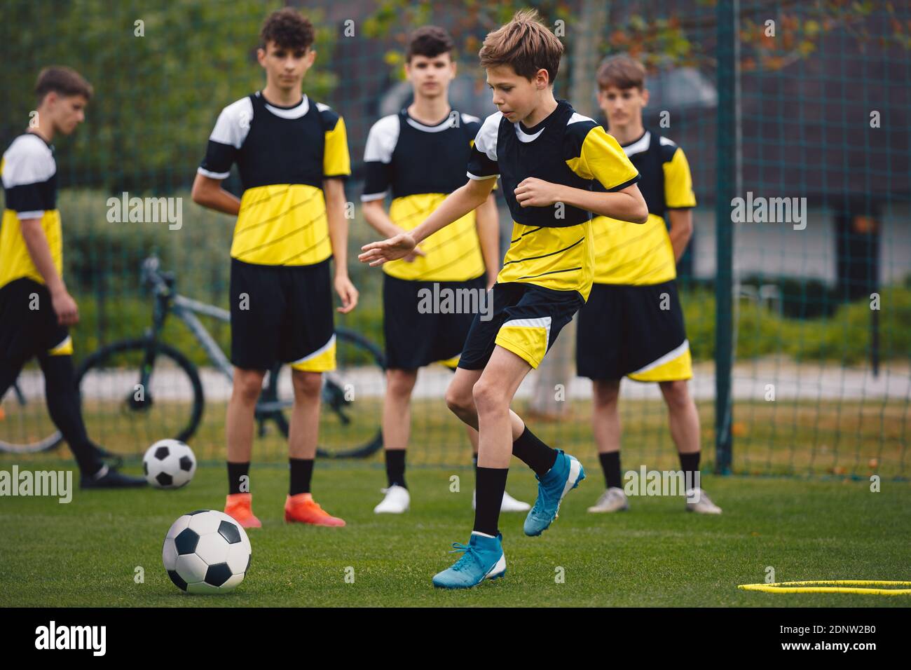 Group of teenage boys on football training. Young soccer players kicking ball on practice. School age boys improving sports skills on school training Stock Photo