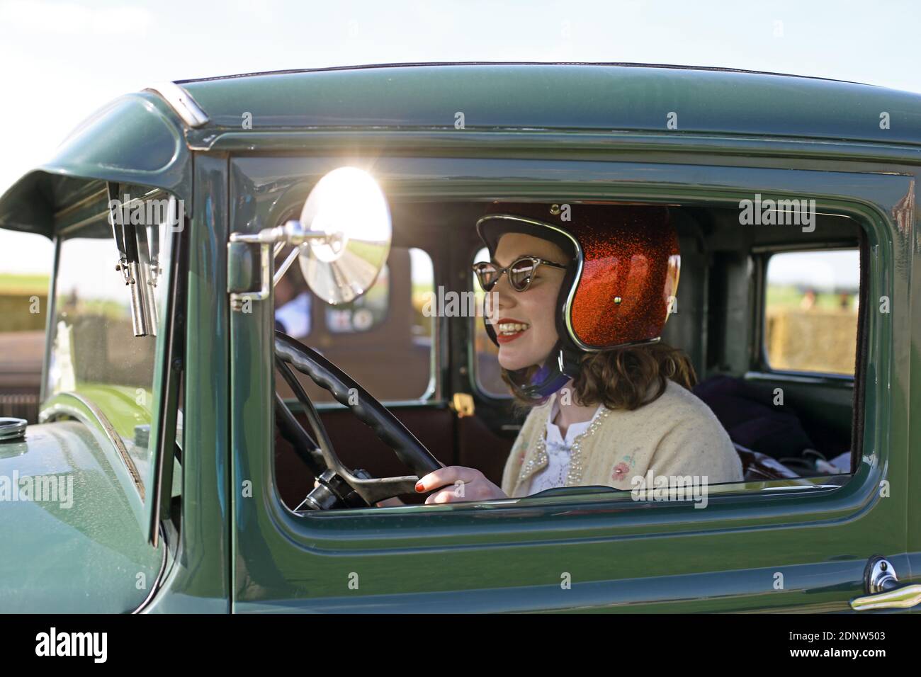 Smiling attractive girl with helmet sitting in vintage car Stock Photo