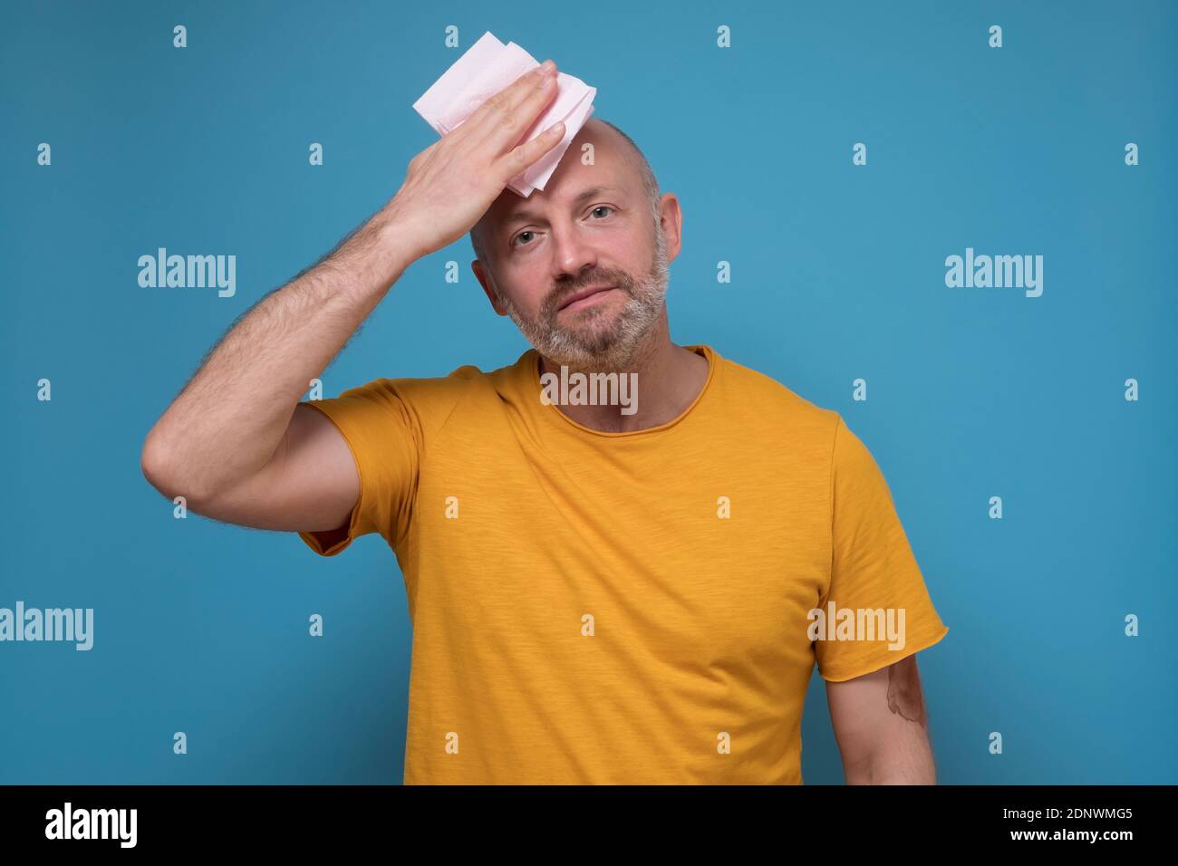 Tired old man with mustache stressed sweating having fever headache. Worried guy wipes sweat on his face Stock Photo