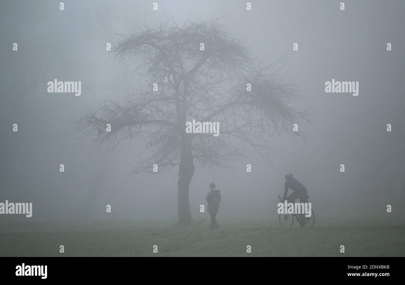 Hanau Steinheim, Germany. 18th Dec, 2020. A cyclist and a walker are on the banks of the river Main in Steinheim in the fog. Credit: Arne Dedert/dpa/Alamy Live News Stock Photo