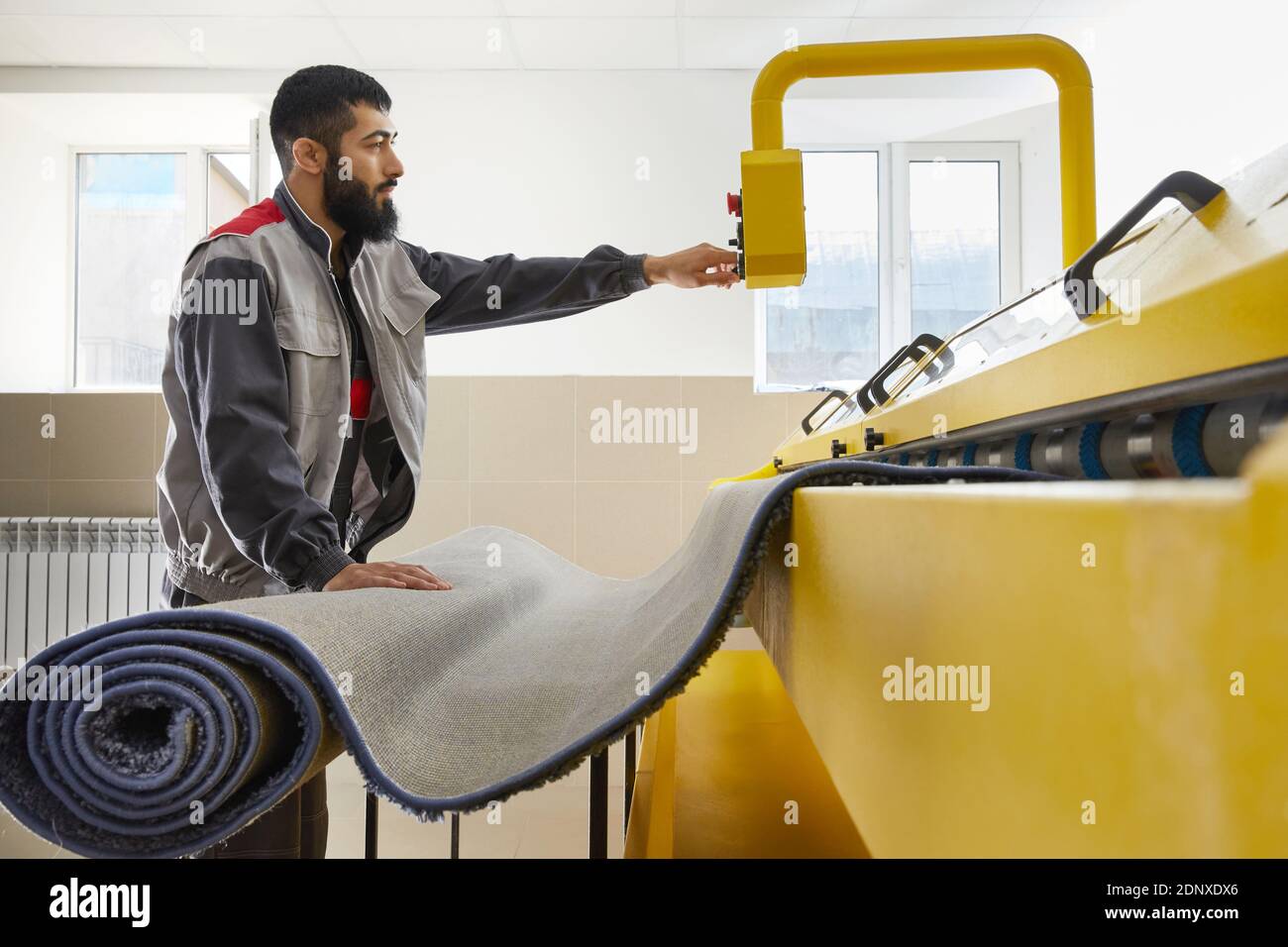Man operating carpet automatic washing machine in professional laundry service Stock Photo