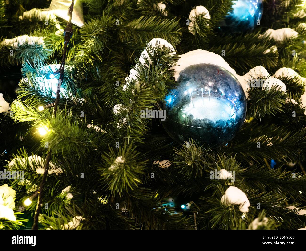 snow and ball on decorated Christmas tree close up outdoors at night Stock Photo