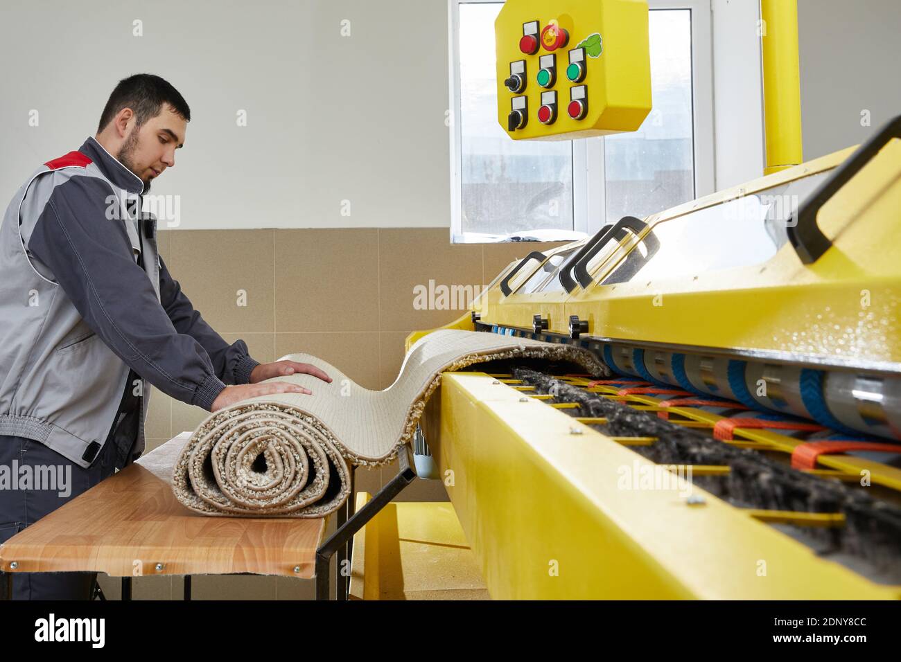 Man operating carpet automatic washing machine in professional laundry service Stock Photo