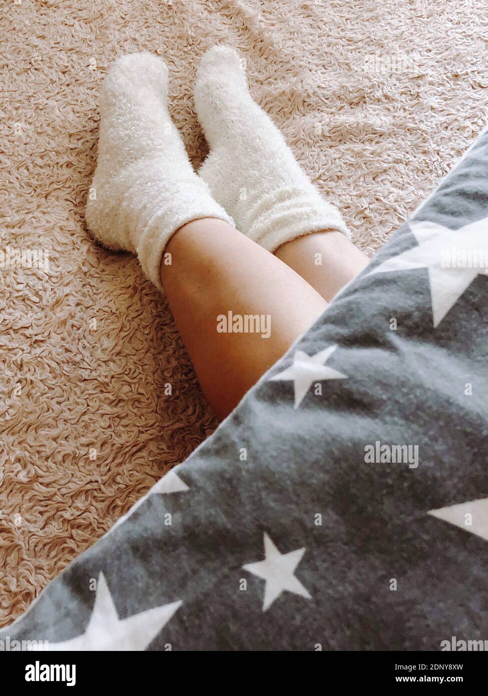 Low Section Of Person Wearing Sock Lying On Carpet At Home Stock Photo