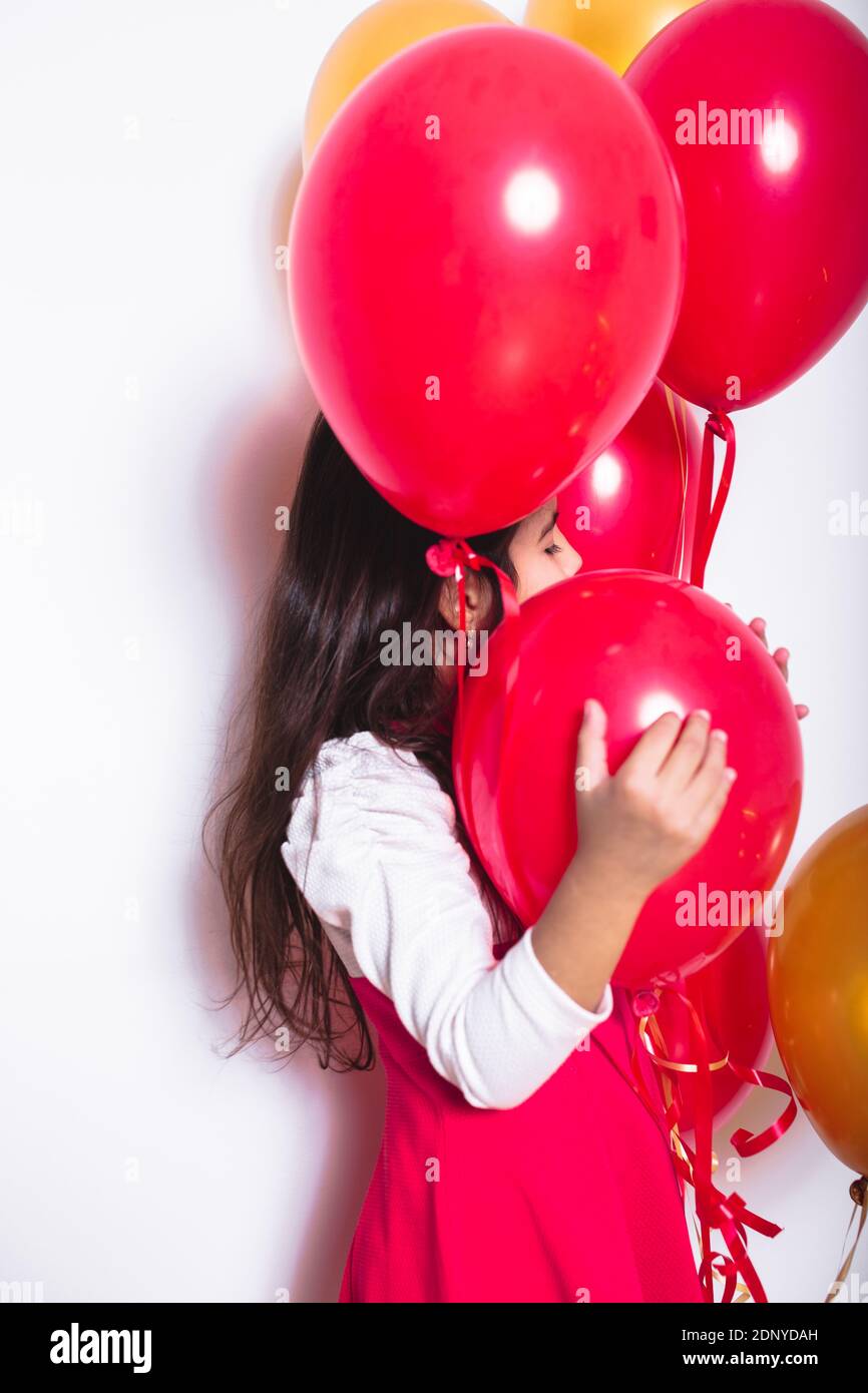 Girl Holding Balloons While Standing Against White Background Stock Photo Alamy