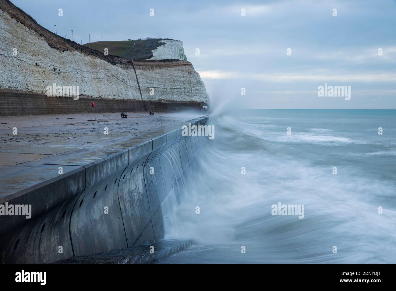 Waves crashing into the sea wall along the undercliff walk from Saltdean to the Telscombe Cliffs East Sussex south east England Stock Photo