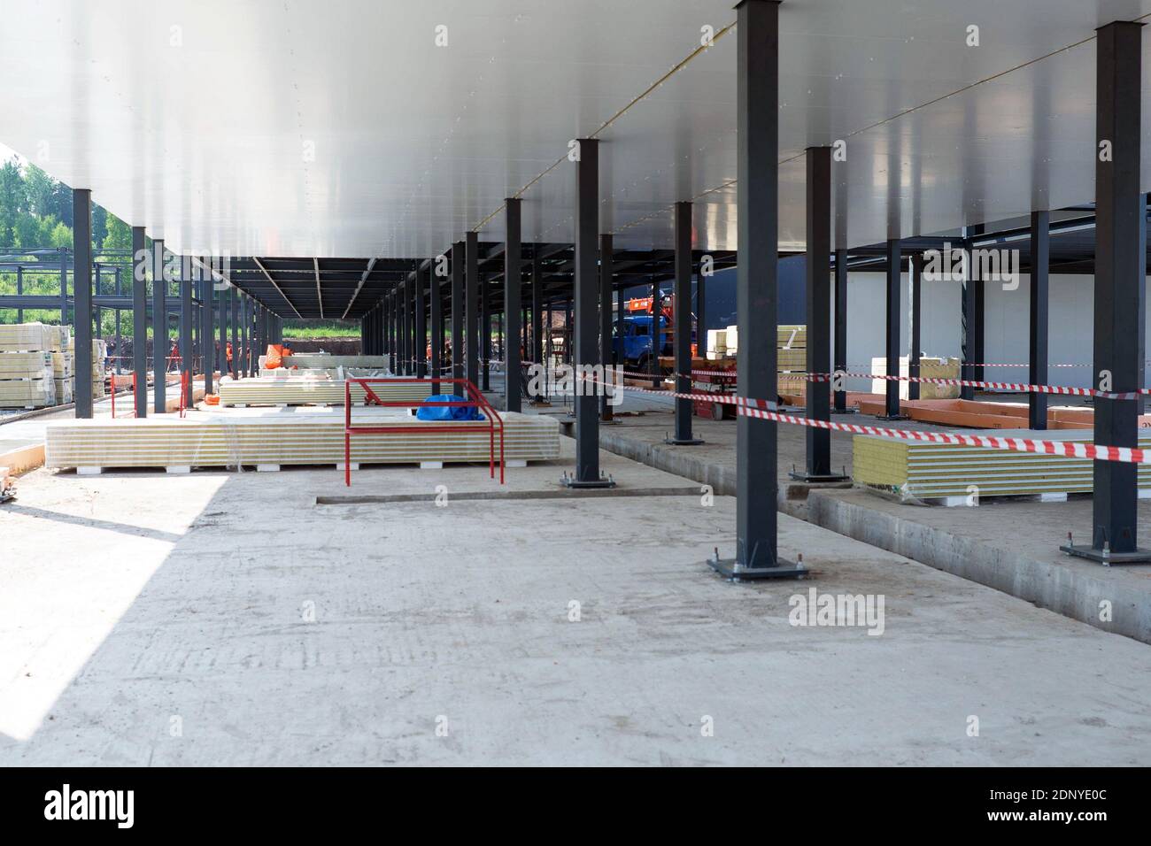 Insulated wall panels lie on a construction site between the metal columns of a medical aid and rescue center under construction on a sunny summer day Stock Photo