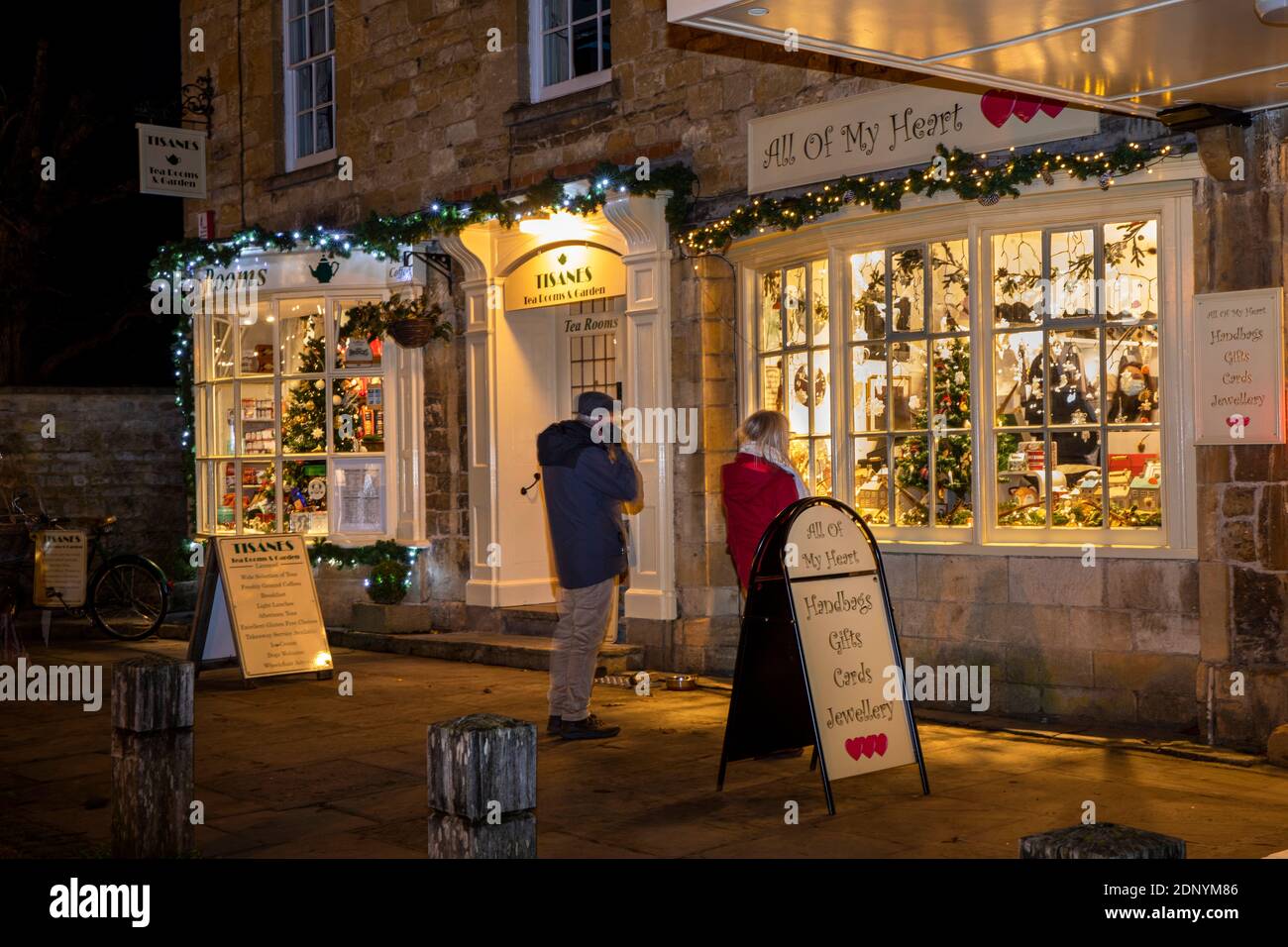 UK, Gloucestershire, Broadway, The Green, Tisanes Tea Room and All Of My Heart gift shop illuminated for village late night Christmas shopping Stock Photo