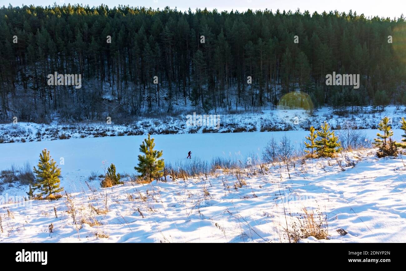 Winter landscape of forest and snow-covered river and skier walking along the river. Beauty in nature, tourism, active lifestyle Stock Photo