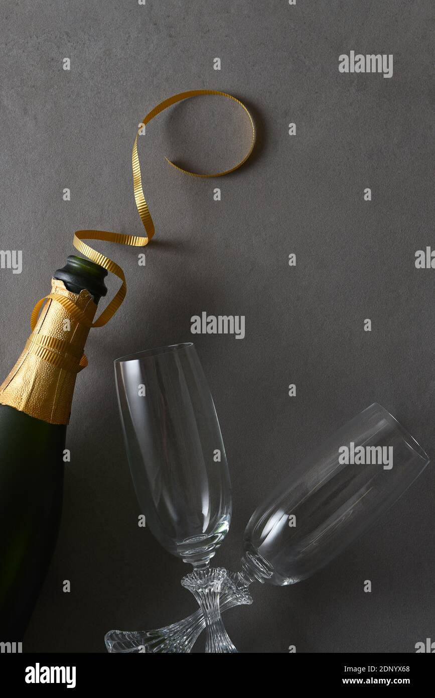 Champagne bottle with god ribbon and two glasses on a gray table. Stock Photo