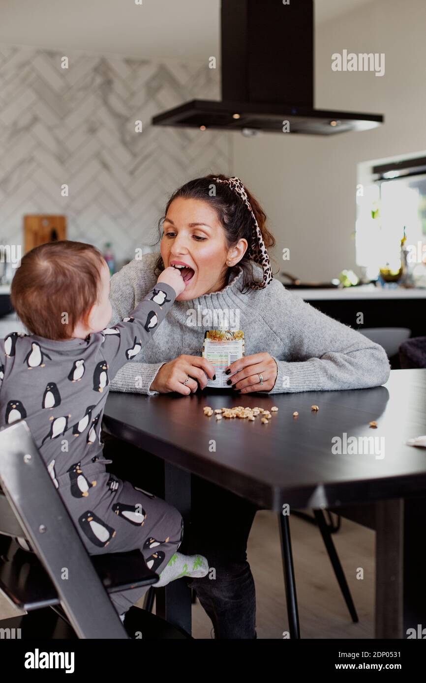 Mother carry toddler son sitting at table Stock Photo