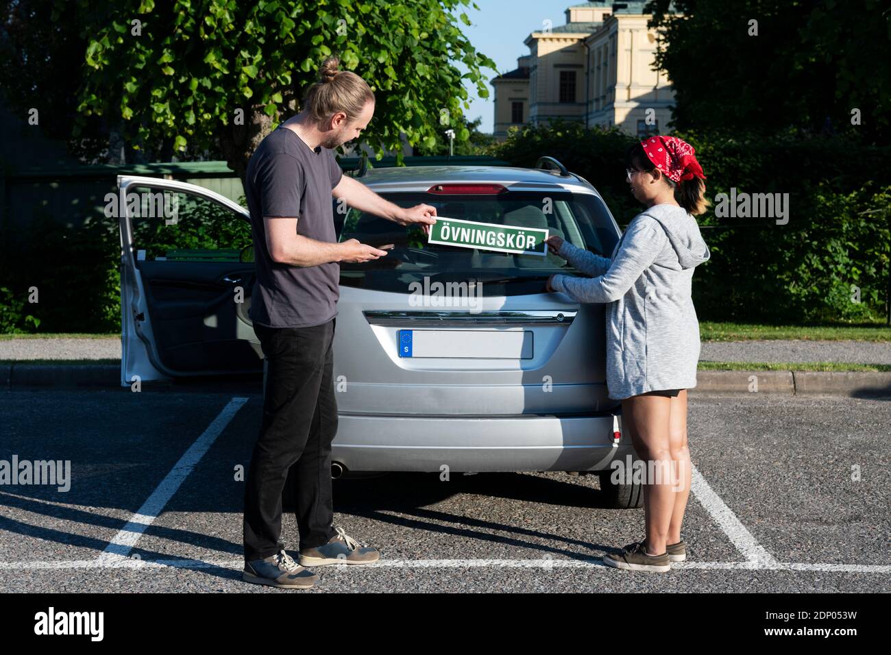 Man and woman putting learning plate on car Stock Photo