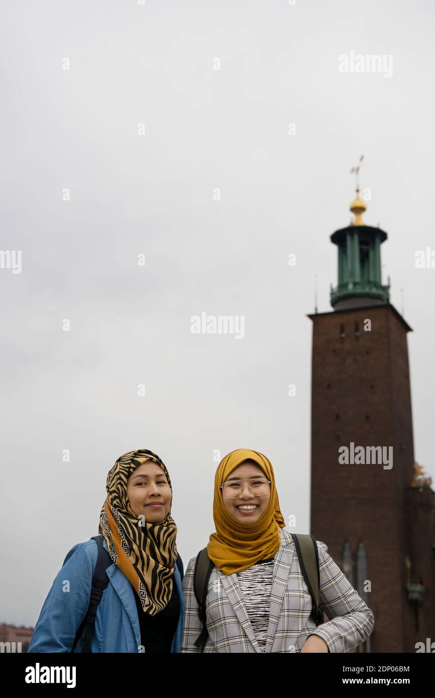 Female friends looking at camera, Stockholm City Hall on background,  Stockholm, Sweden Stock Photo - Alamy