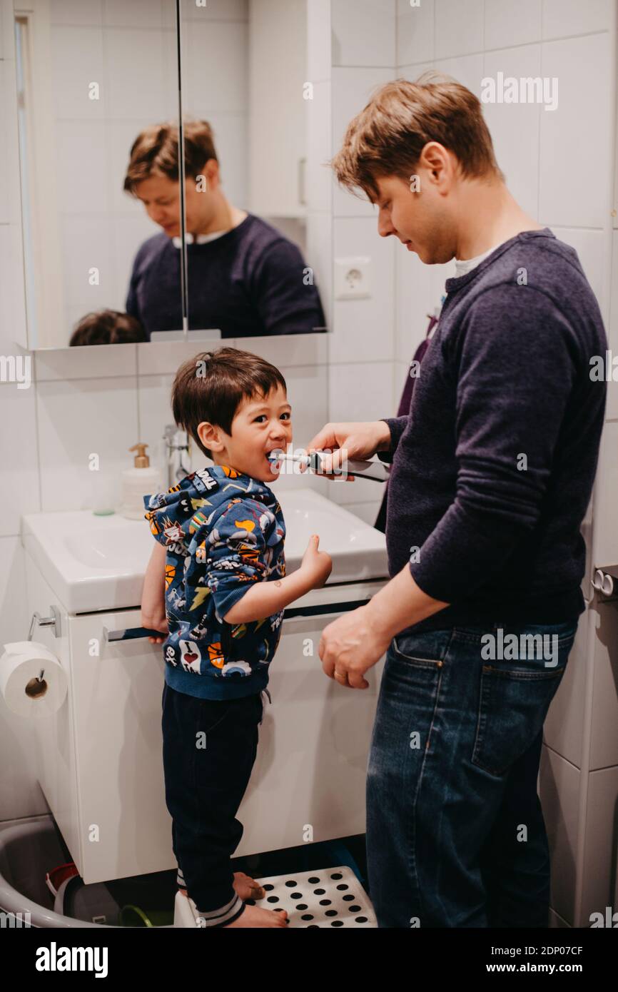 Father helping son brush his teeth Stock Photo