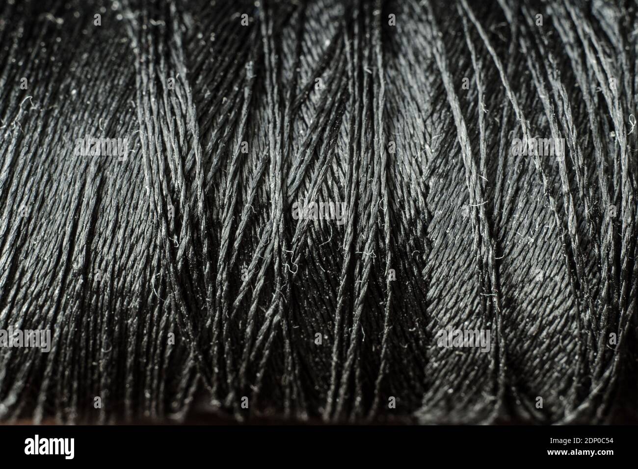 Close-up of a black thread and needle on a dark surface