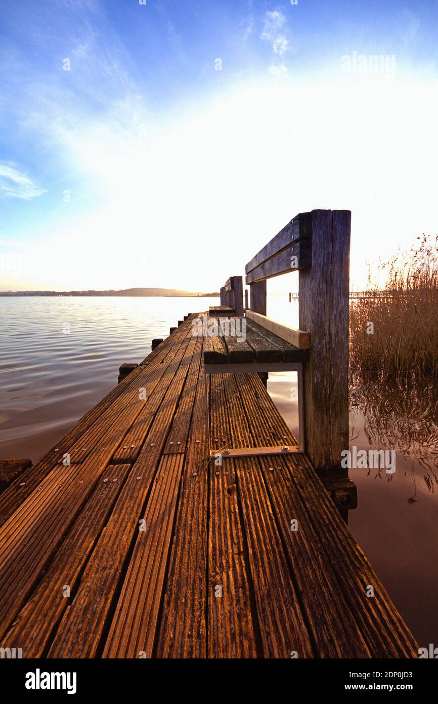 December 16, 2020, Schleswig, a weathered wooden pier with banks as the sun slowly sets on the banks of the Schlei. | usage worldwide Stock Photo