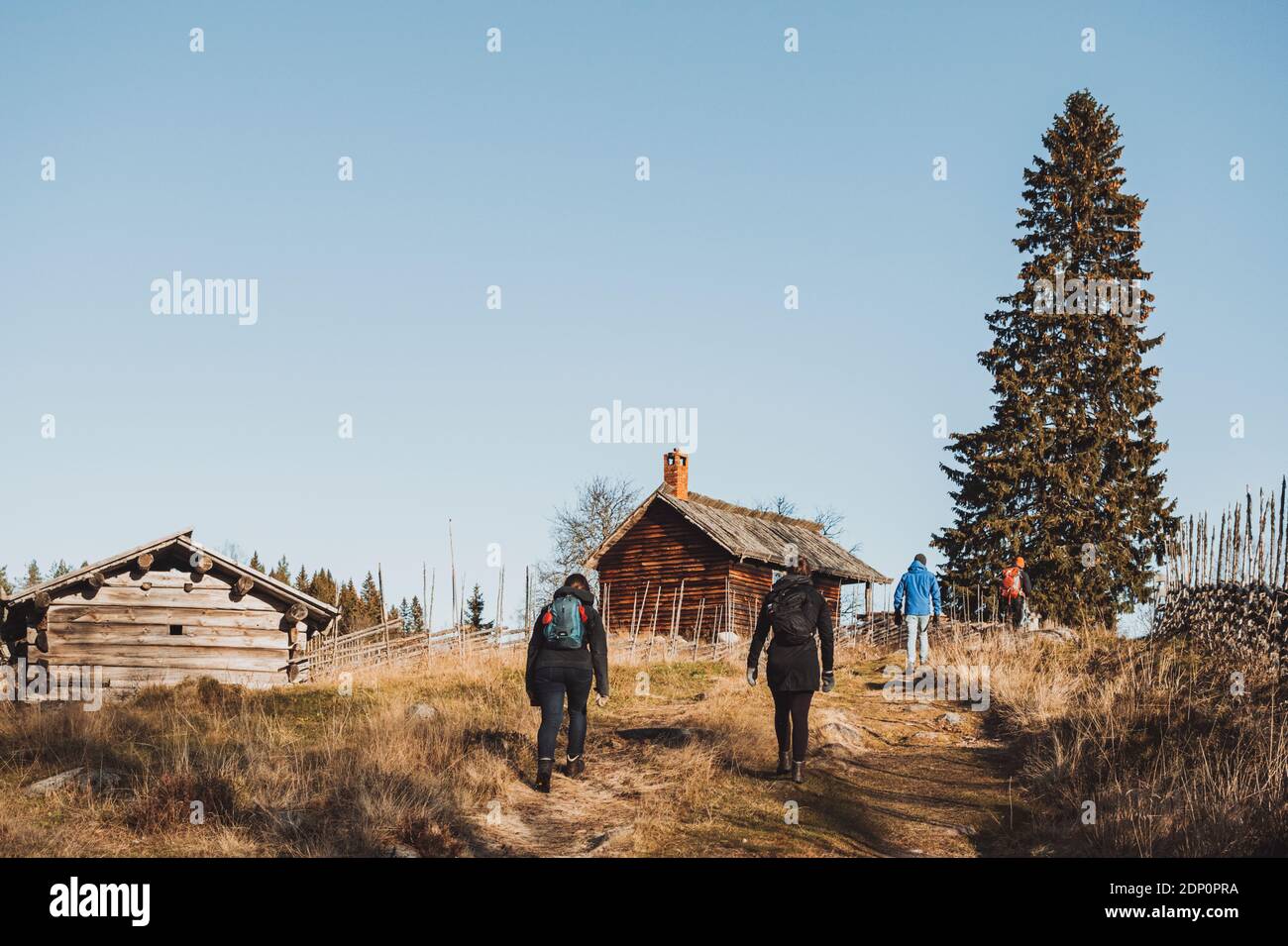 People hiking towards wooden cottages Stock Photo