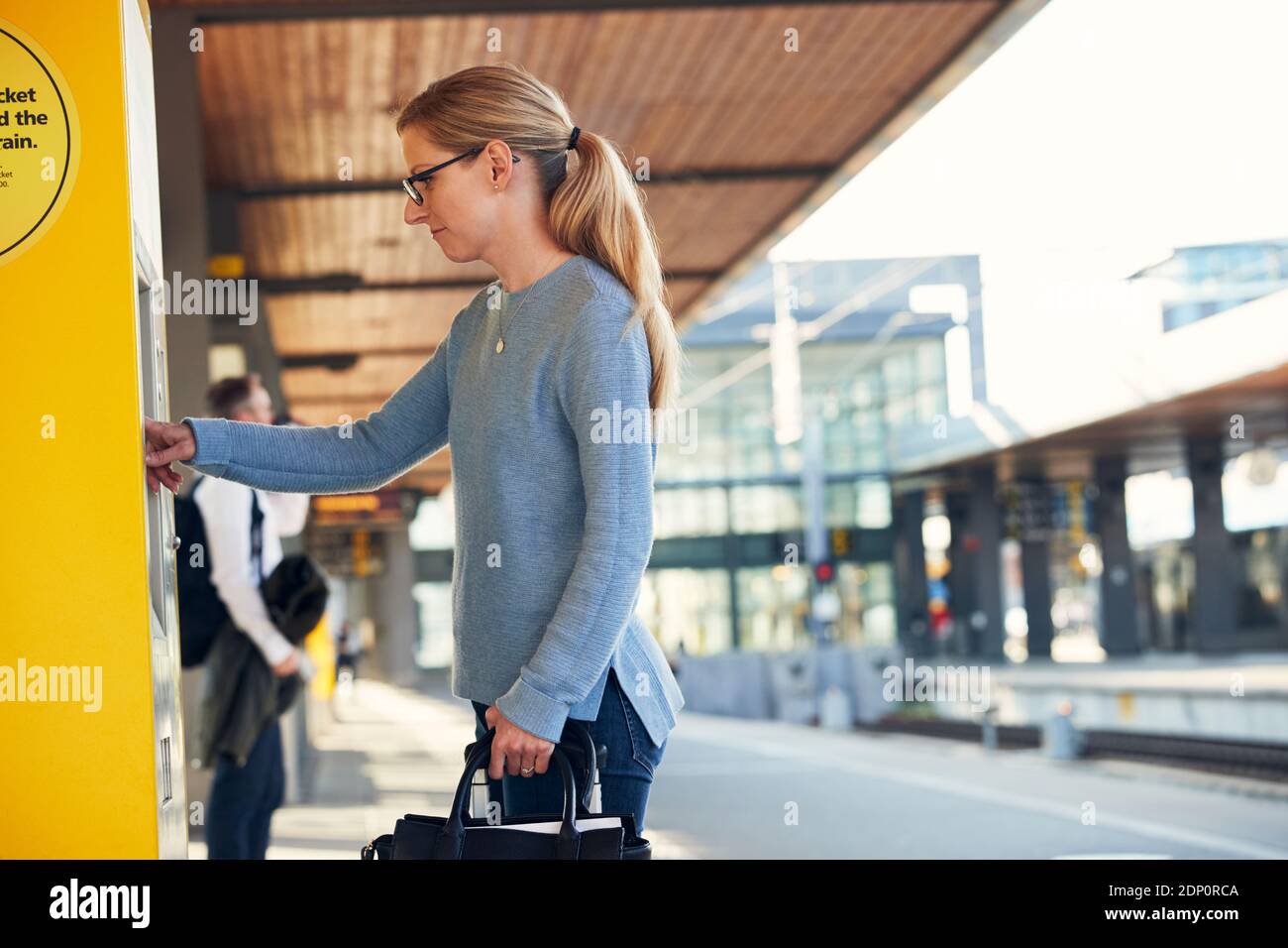 Woman using ticket machine at train station Stock Photo - Alamy